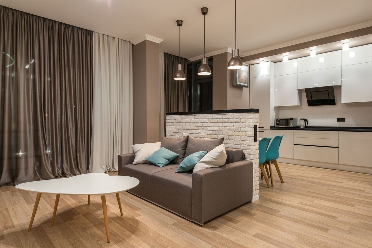 Apartment living room with a sofa opening onto a white kitchen
