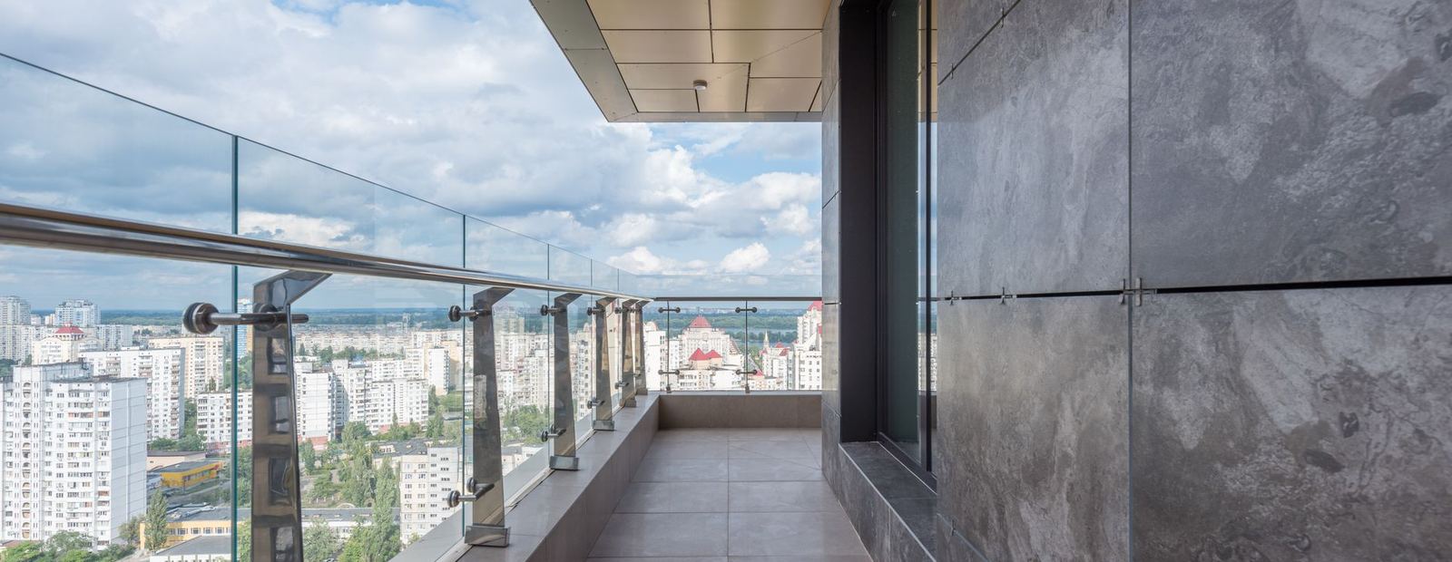 Balcony walkway with a glass rail overlooking a city