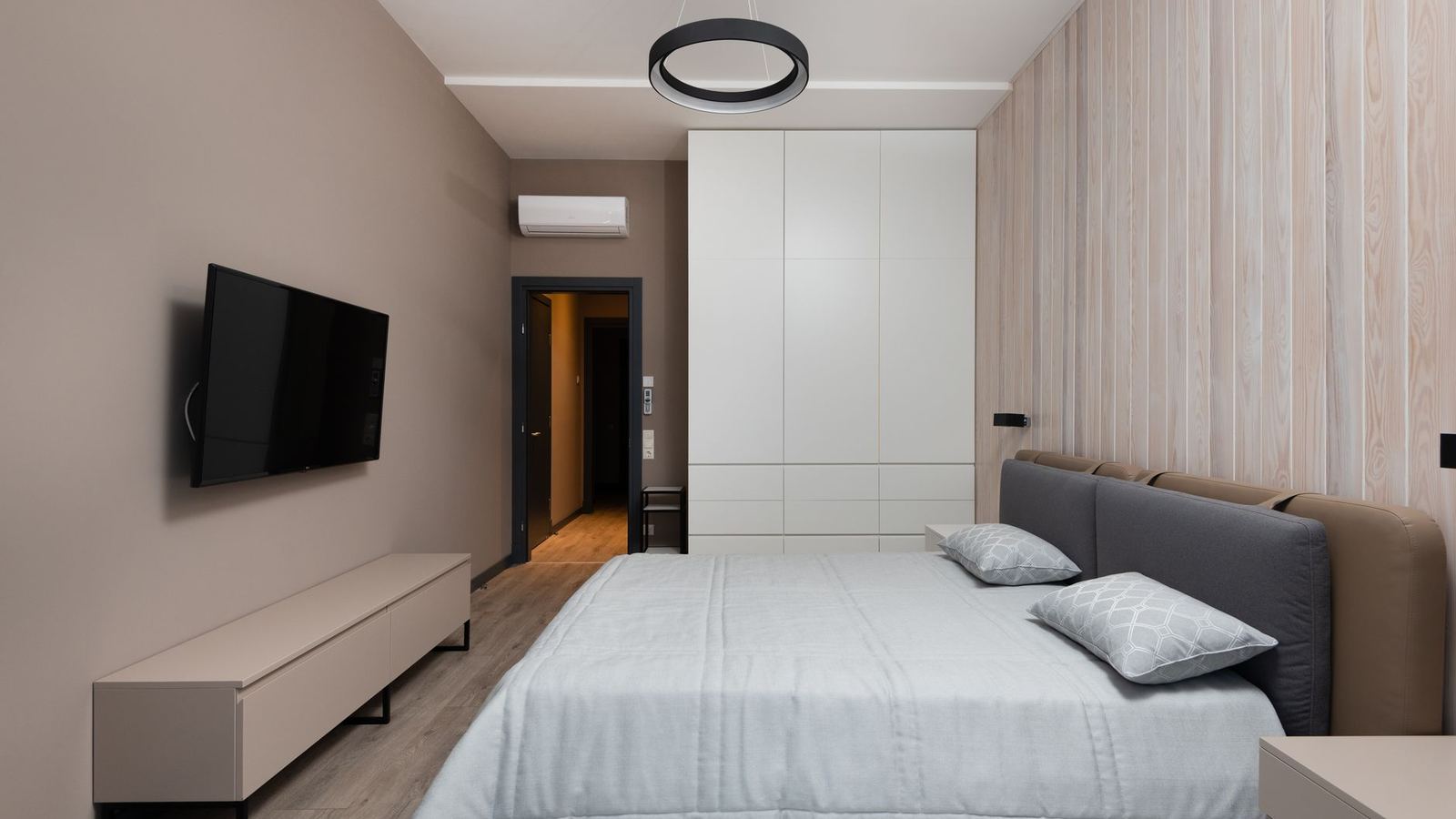 Bedroom with a wall-mounted television and a built-in wardrobe