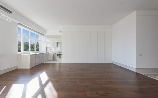 Empty apartment living area with wood floors and an open kitchen