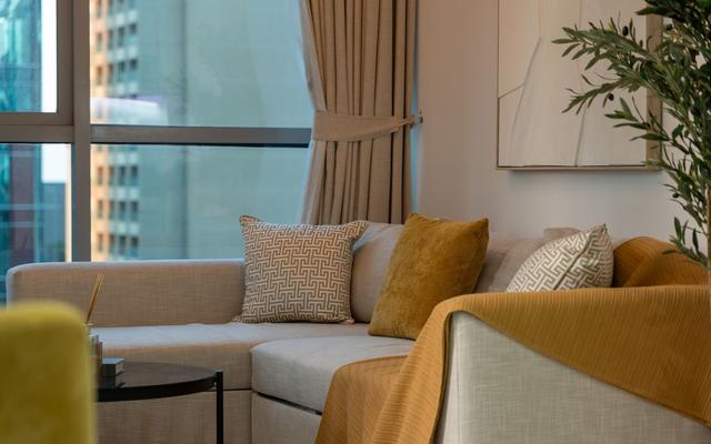 Sofa with cushions and a folded throw beside a city window