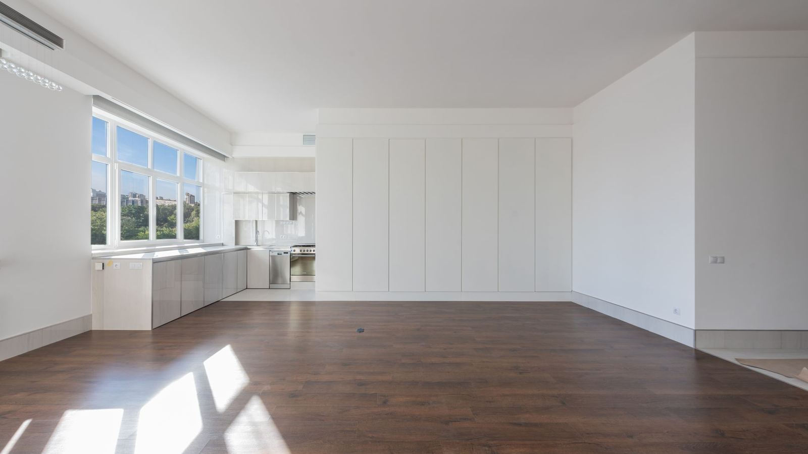Empty apartment living area with wood floors and an open kitchen