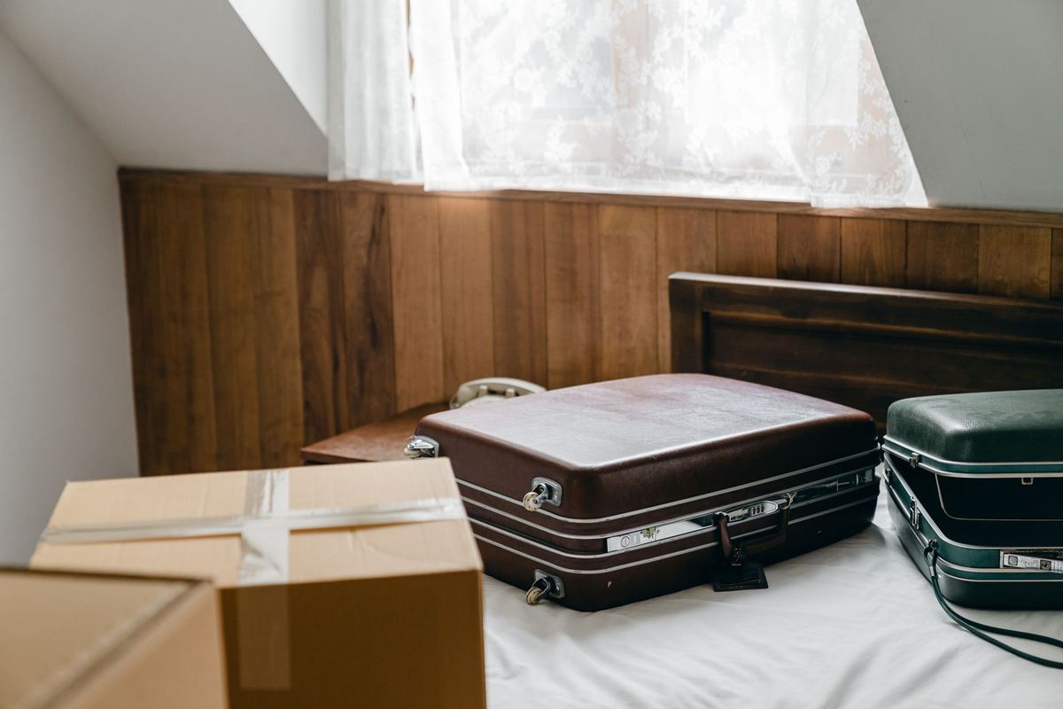 Two packed suitcases and a taped box on a bed